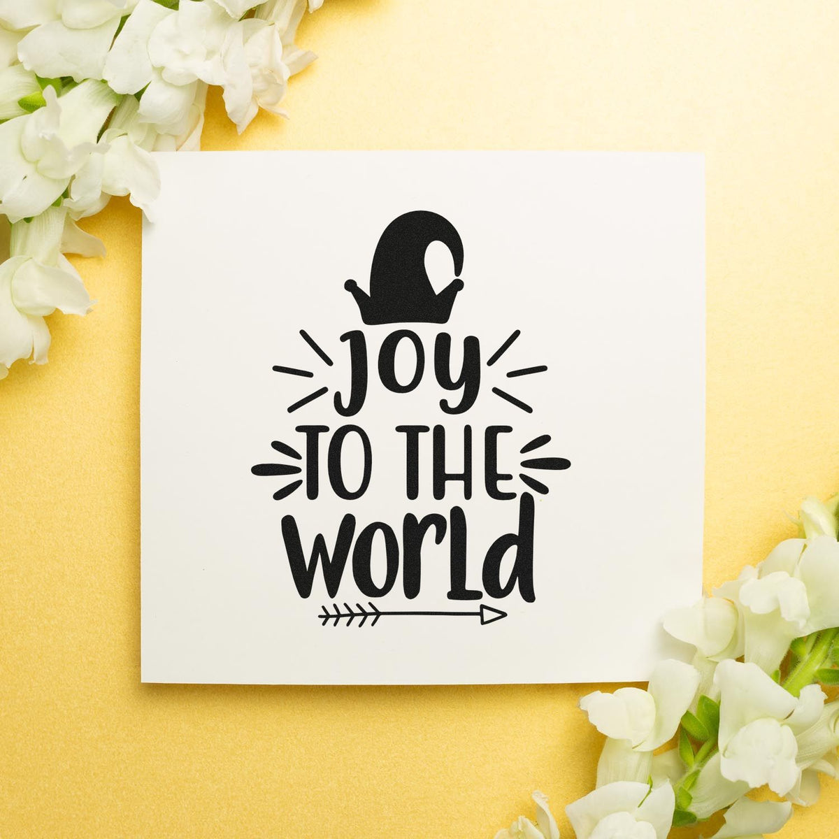 Black Joy to the World stamp and seal design on white card, framed by white flowers on a soft yellow background.