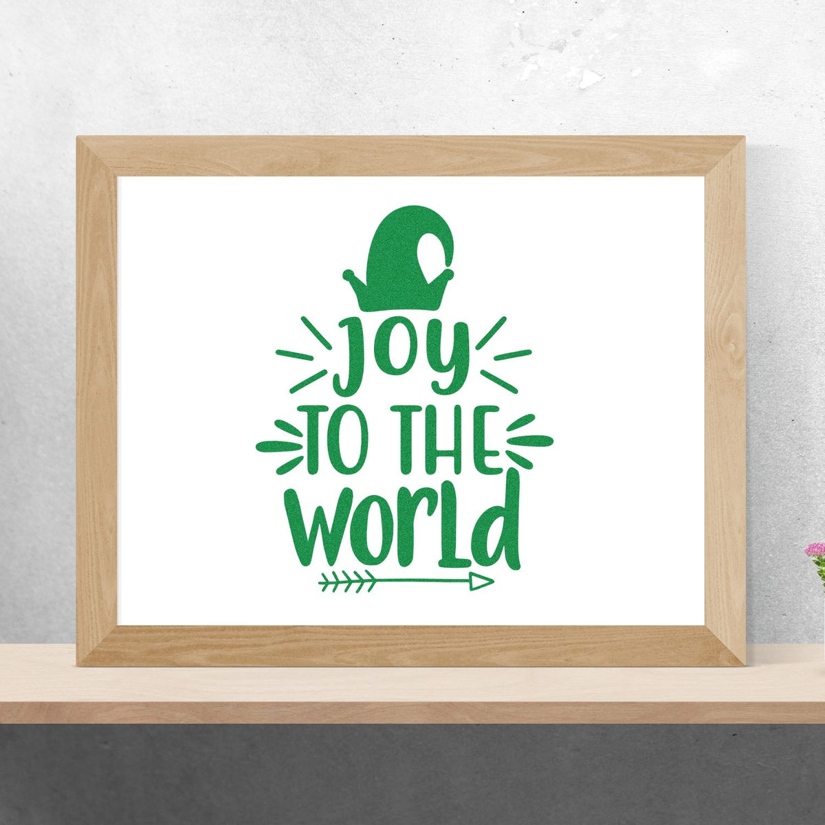 Green stamp-style seal with Joy to the World text, framed on white, featuring a festive ornament and arrow accents.