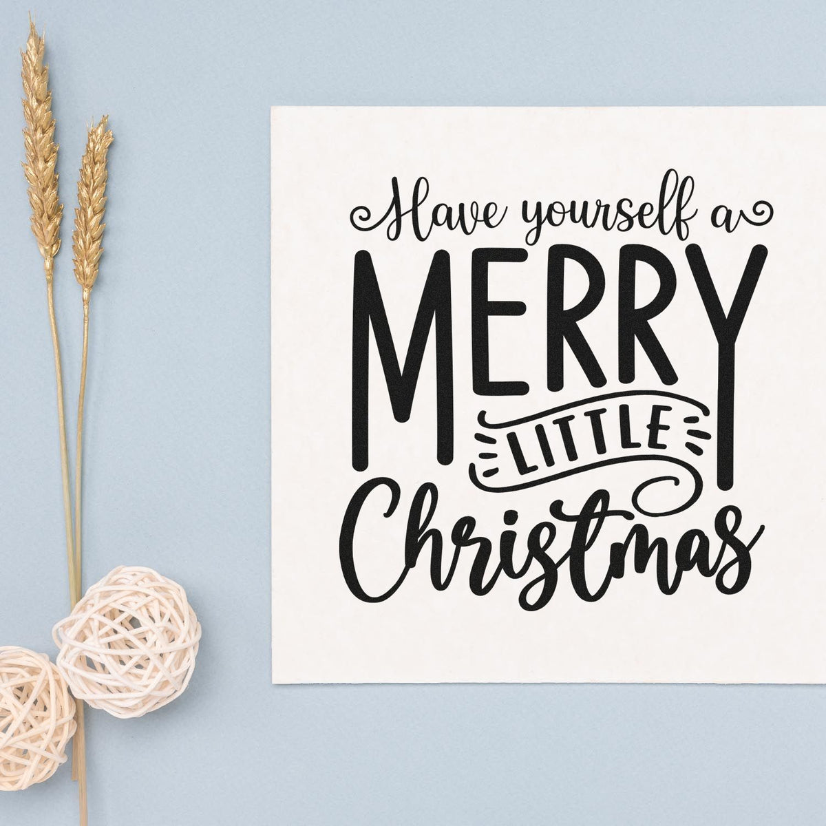 Black Merry Little Christmas stamp on white card, with blue background and gold wheat stems, for festive stamp and seal products.