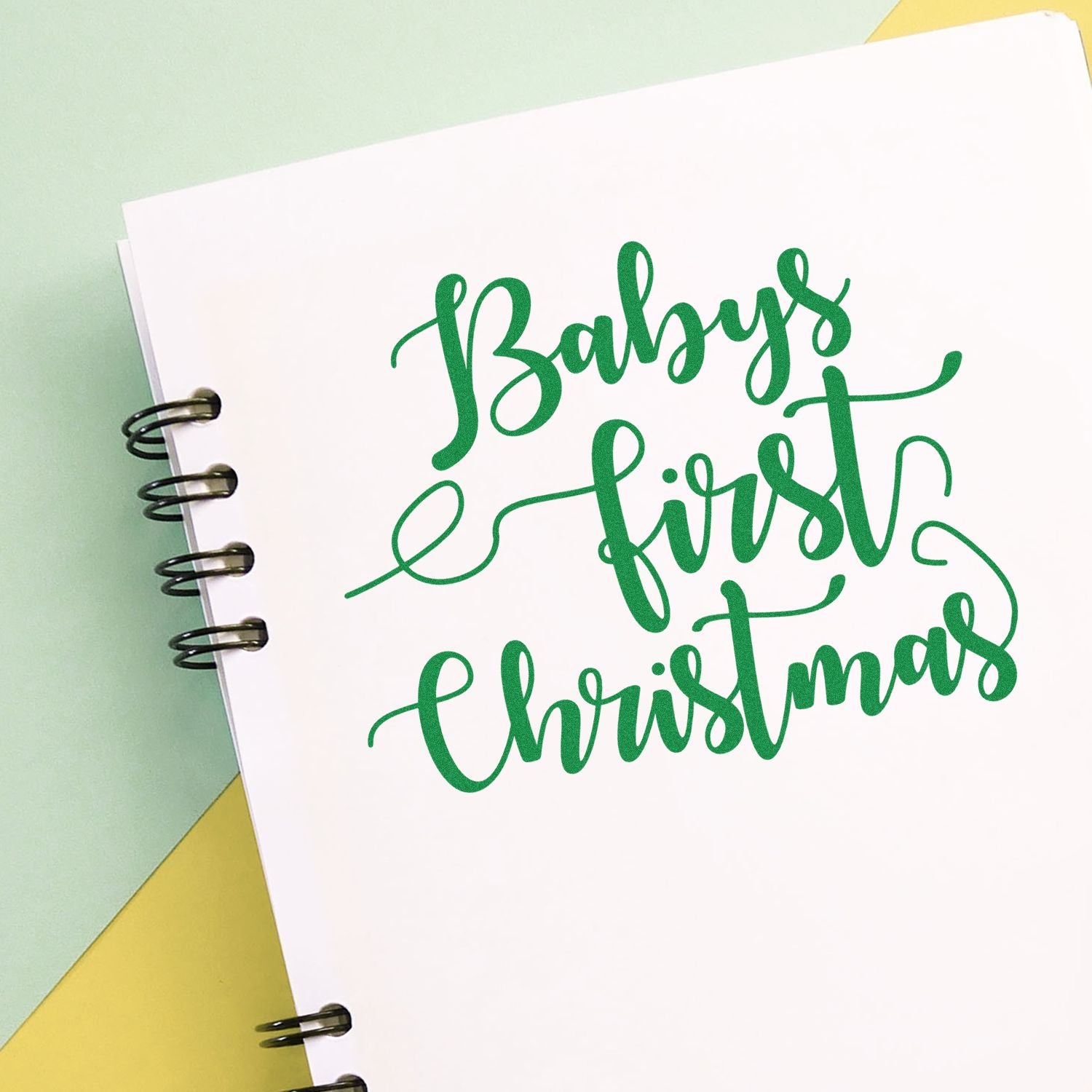 Green Babys First Christmas stamp/seal on white spiral-bound card with mint and yellow background.