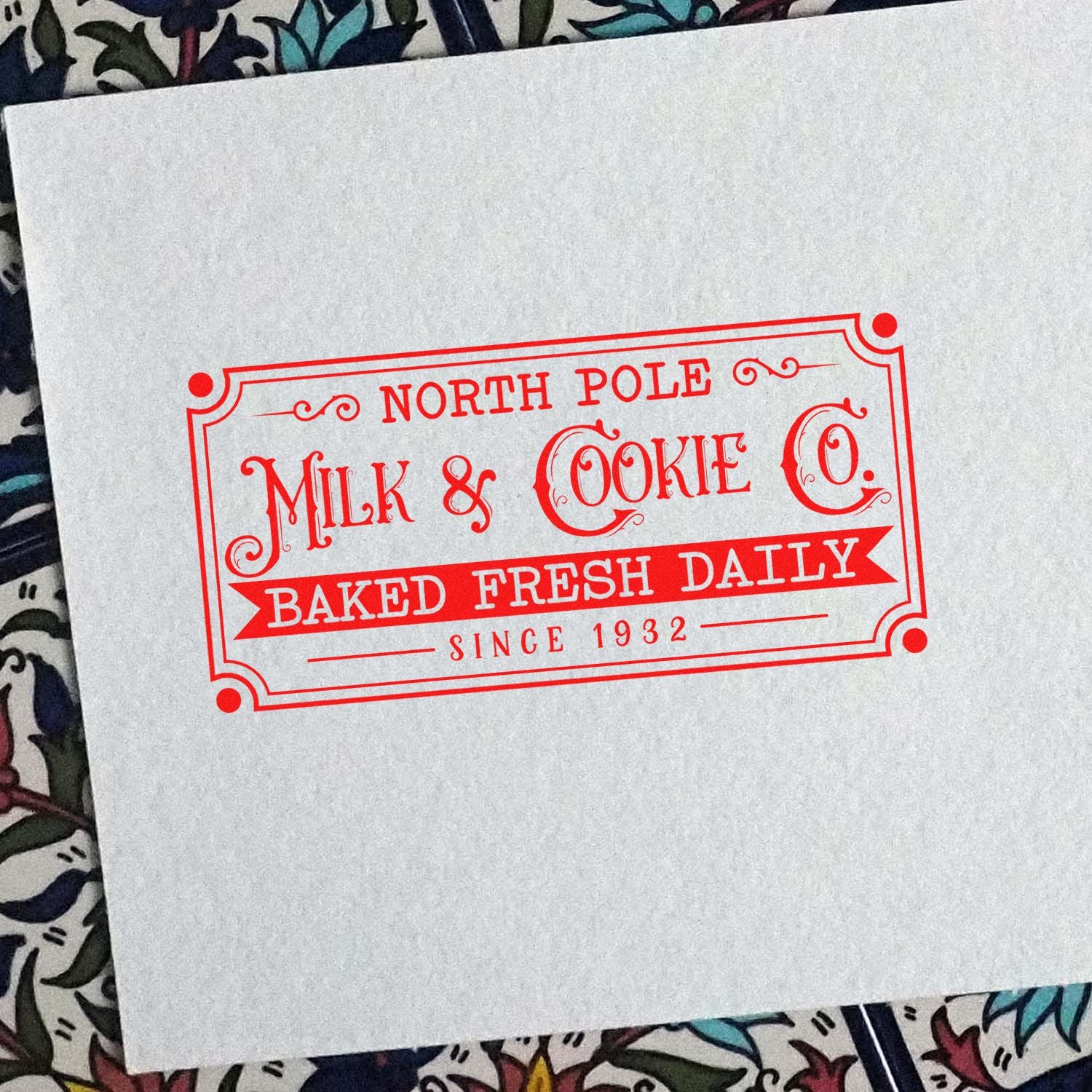 Red North Pole Milk & Cookie Co. stamp seal on white paper, with Baked Fresh Daily and Since 1932.