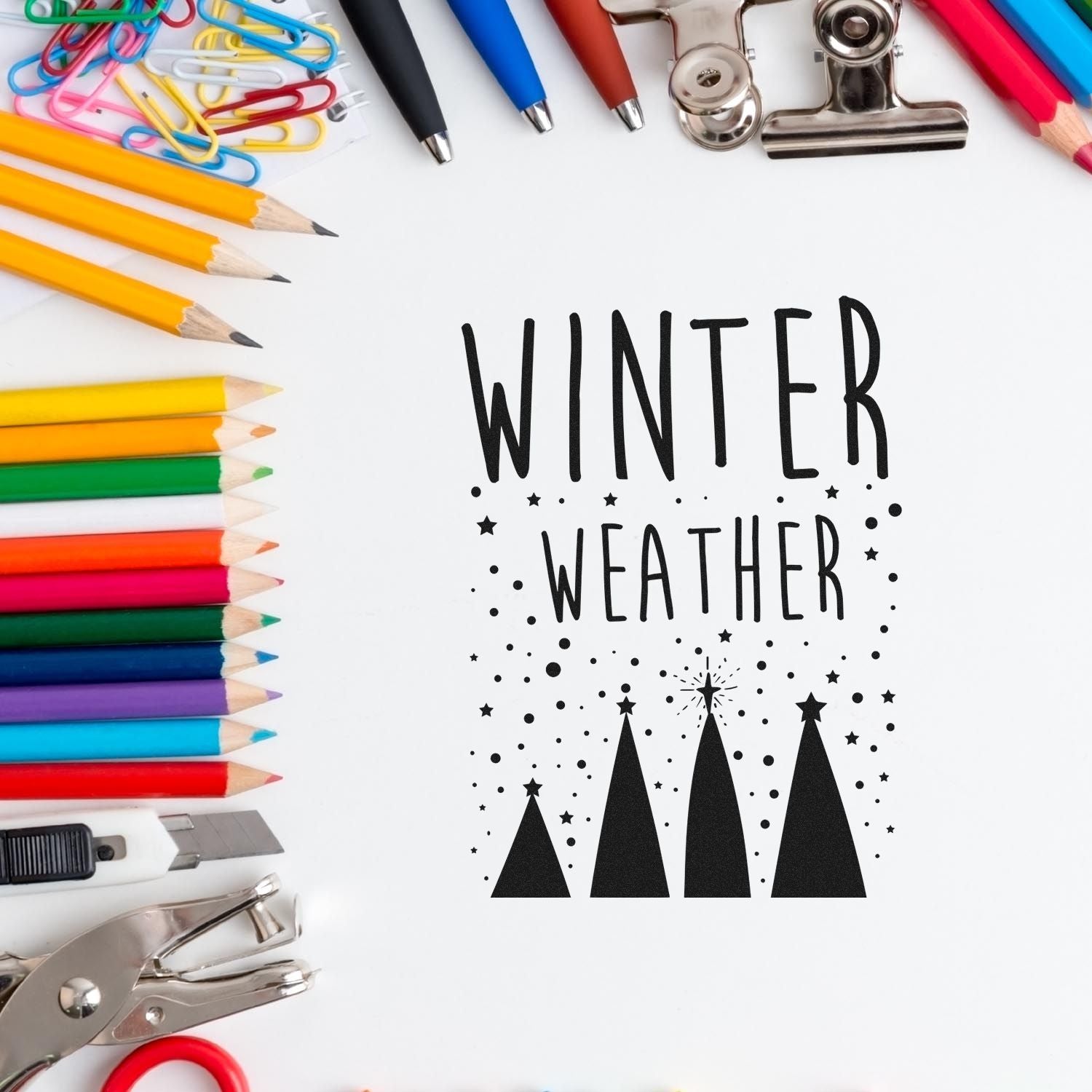 Winter Weather stamp seal in black with trees, surrounded by colorful pencils, paper clips, and silver office tools.