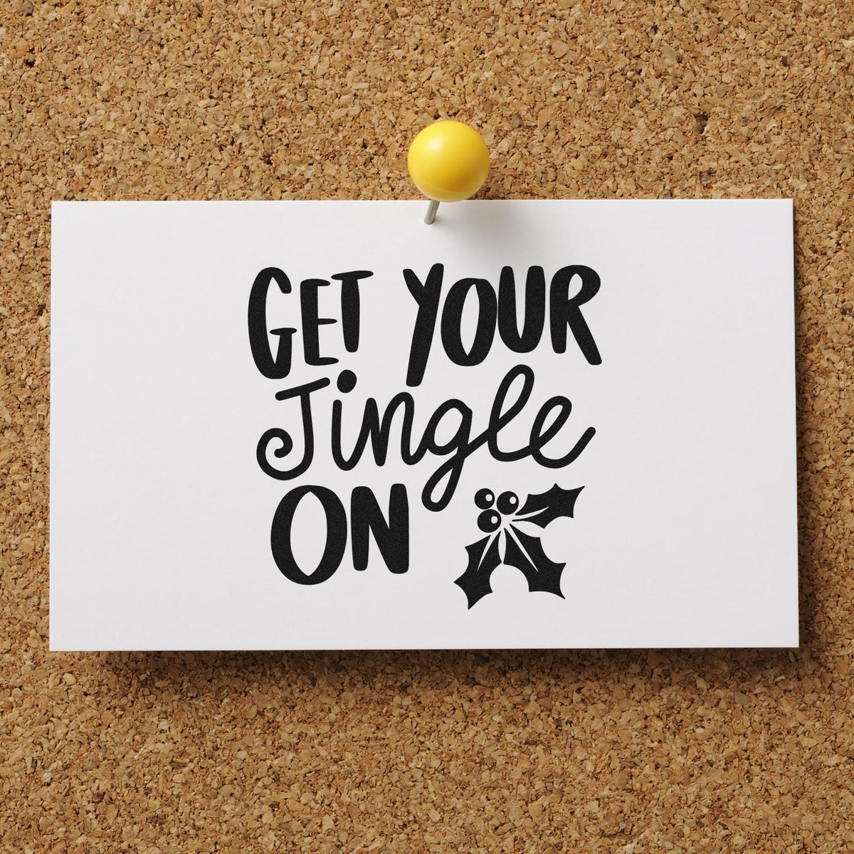Holiday stamp and seal card with black Get Your Jingle On lettering, holly graphic, and yellow pushpin on corkboard.