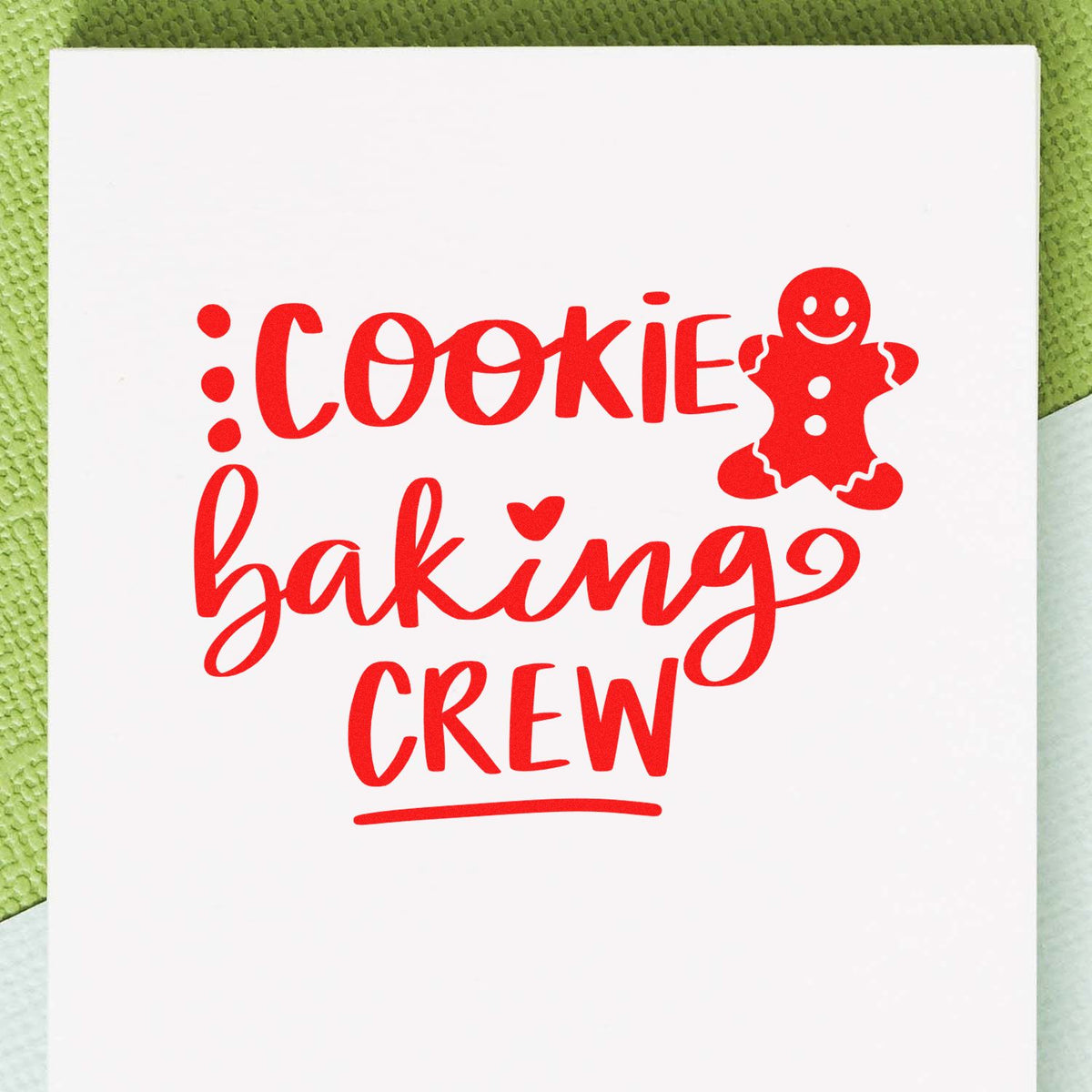 Red cookie baking crew stamp/seal with gingerbread man on white card, on green background