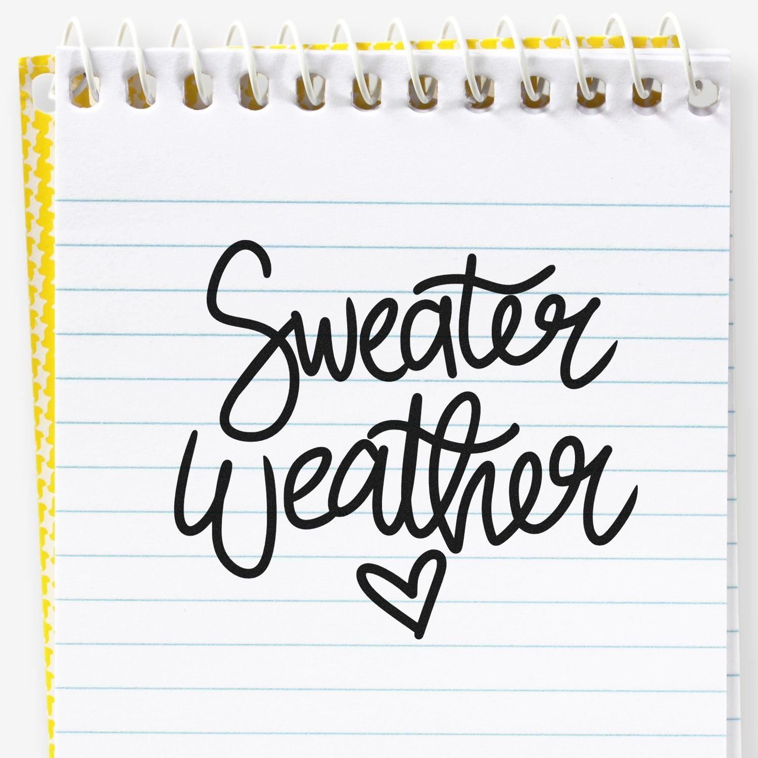 Black Sweater Weather stamp design on white spiral notebook page with blue lines, yellow border, and heart doodle.