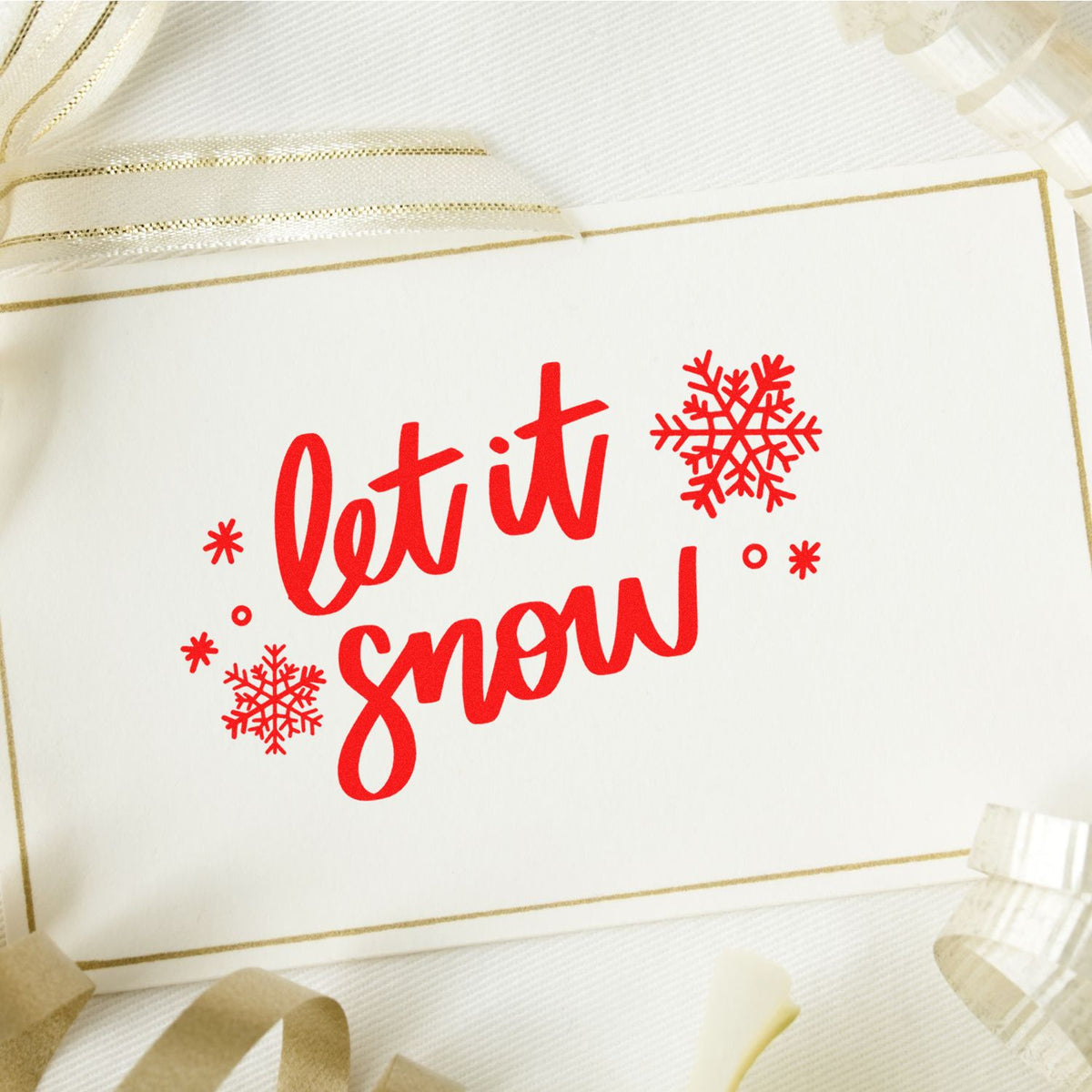Red let it snow holiday stamp with snowflakes, on white card with gold border and ribbon seal accents.