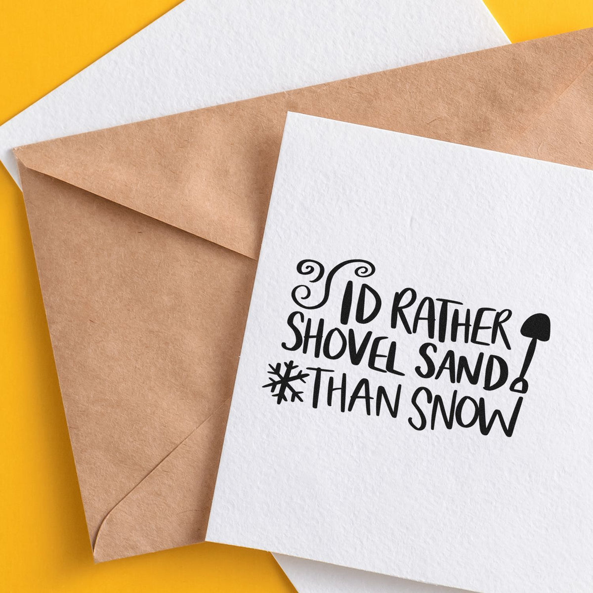 Custom stamp and seal cards with black Id rather shovel sand than snow design on white and kraft paper, against a yellow background.