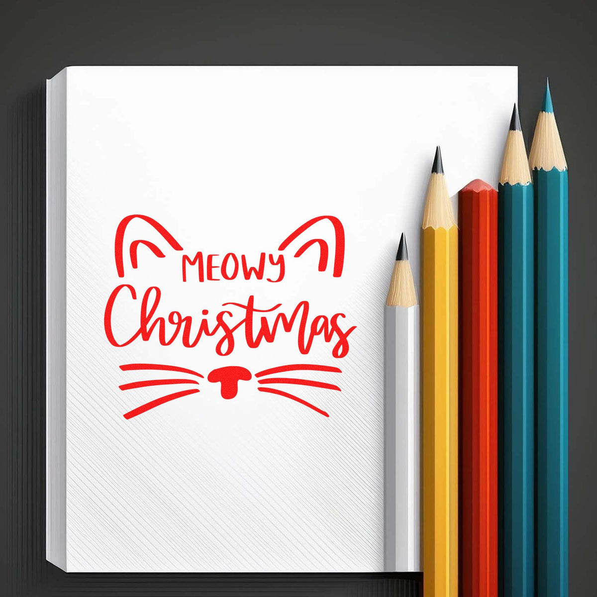 Red Meowy Christmas cat stamp and seal on white notebook, with yellow, orange, teal, and white pencils