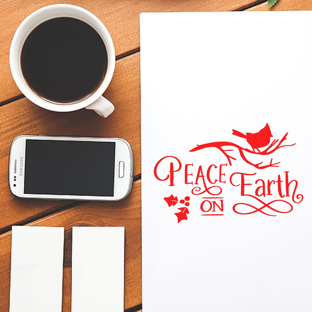 Red Peace Earth stamp seal with bird branch motif on white paper, beside coffee, smartphone and blank cards on a wooden table.