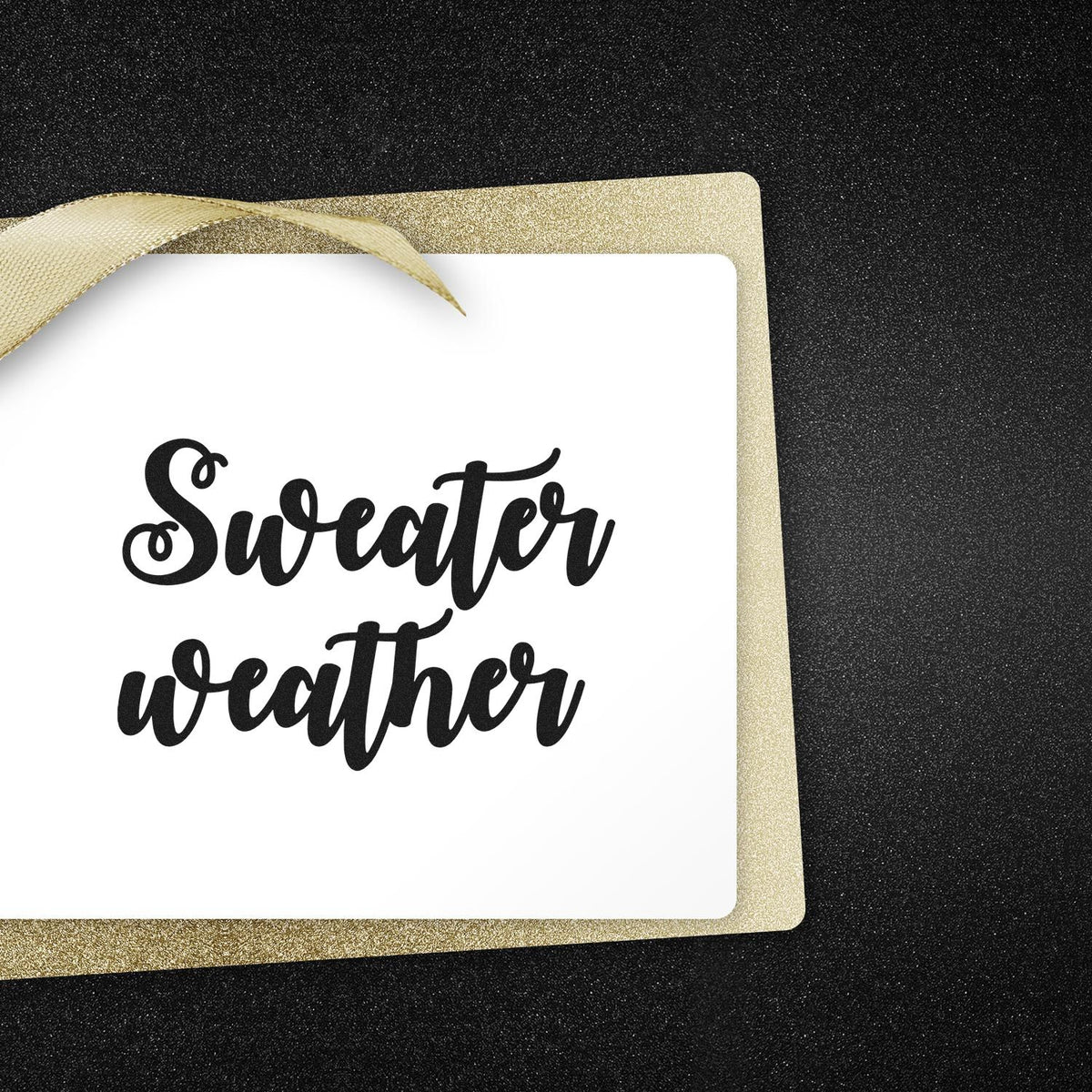 Sweater weather black script stamp and gold glitter seal border with ribbon on white card, set against a black background