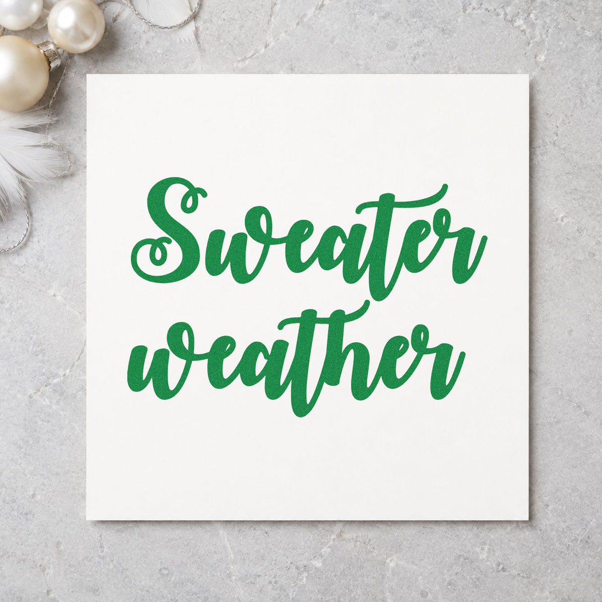 Sweater Weather Brush Script craft stamp imprint in green ink on a handmade project, one idea being shop board signs.