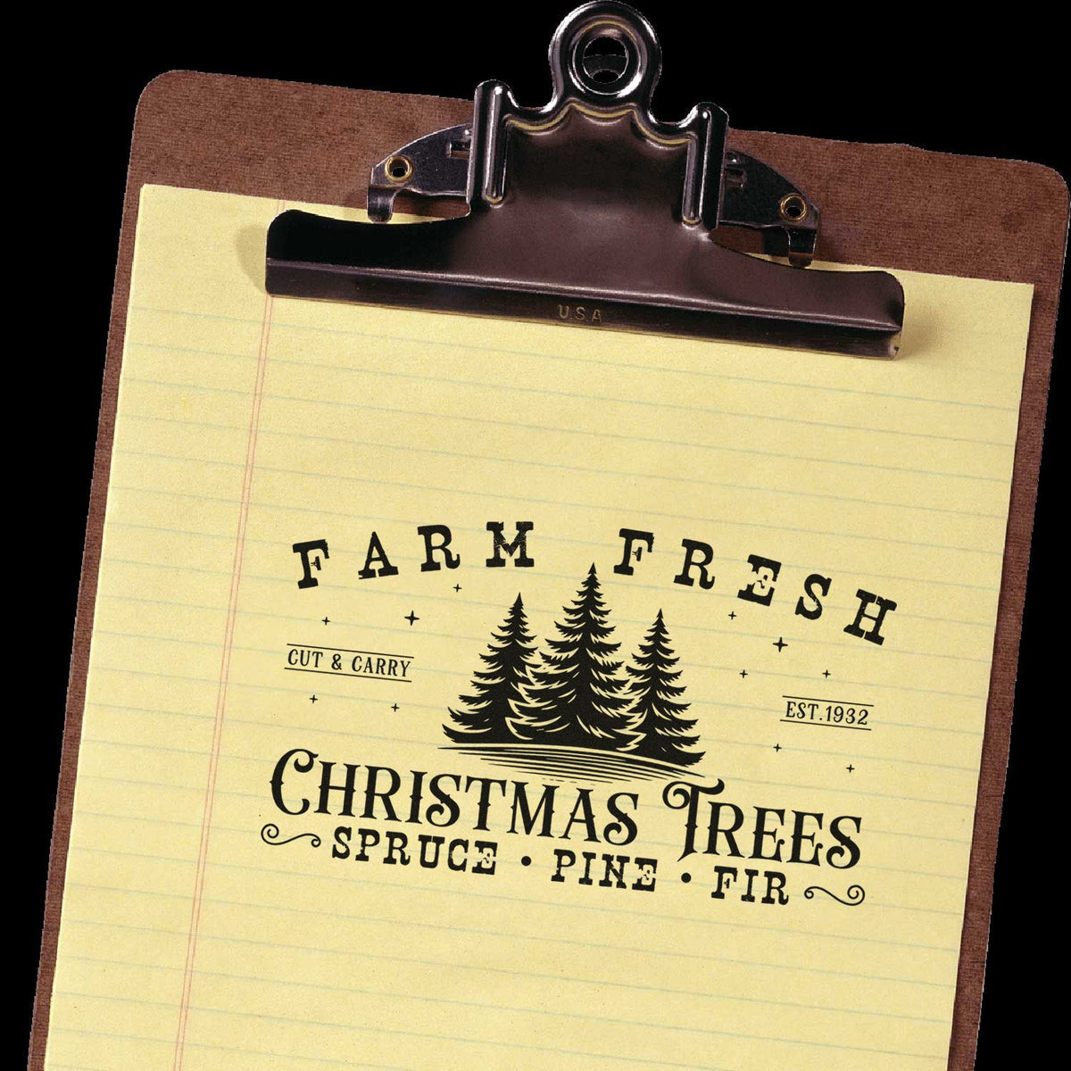 Vintage black clip stamp on yellow paper, reading Farm Fresh Christmas Trees with pine tree seal on a brown clipboard.
