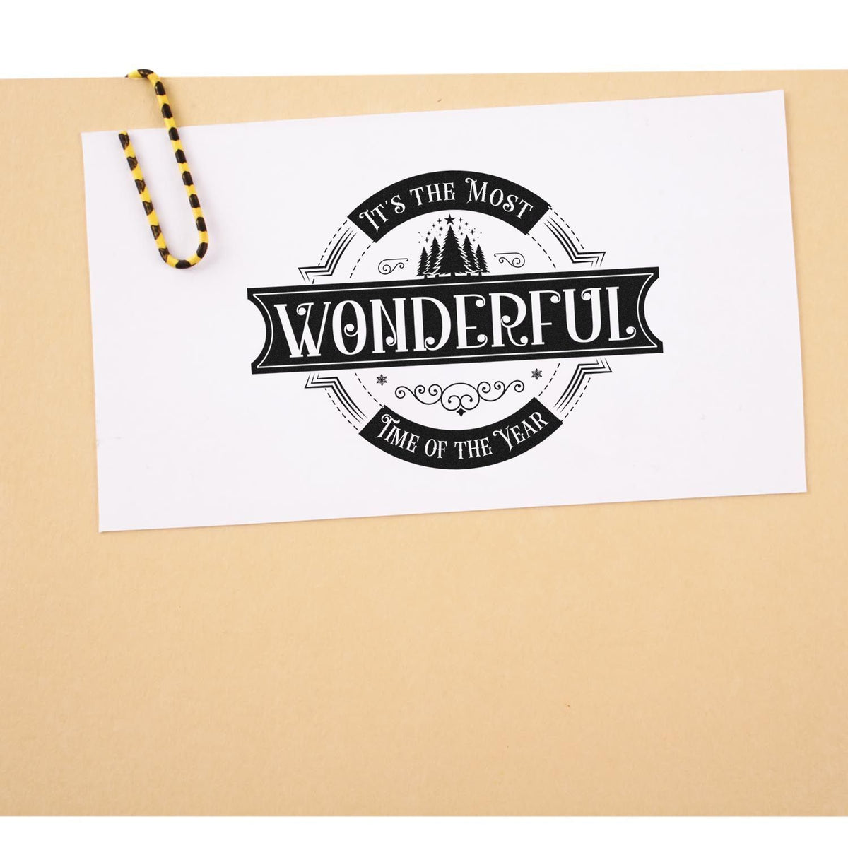 Black vintage stamp seal with Its the Most Wonderful Time of the Year on white paper, clipped to a beige background.
