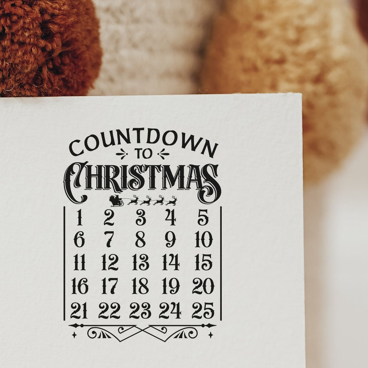 Black Countdown to Christmas stamp seal on white paper, with 125 number grid and festive sleigh graphic.