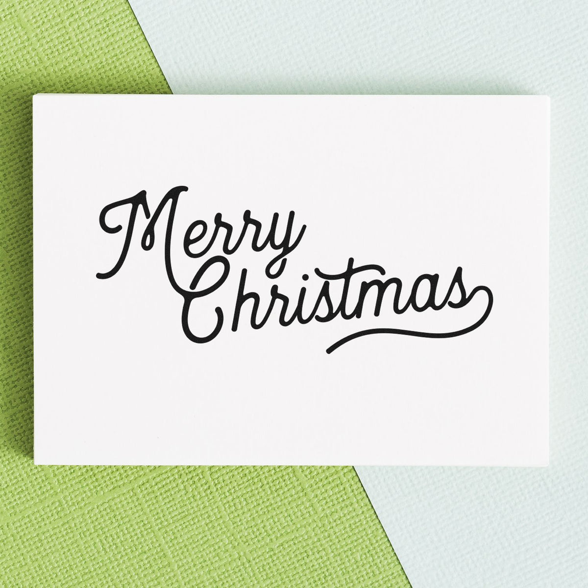 Black Merry Christmas stamp and seal on white card over green and white textured background.