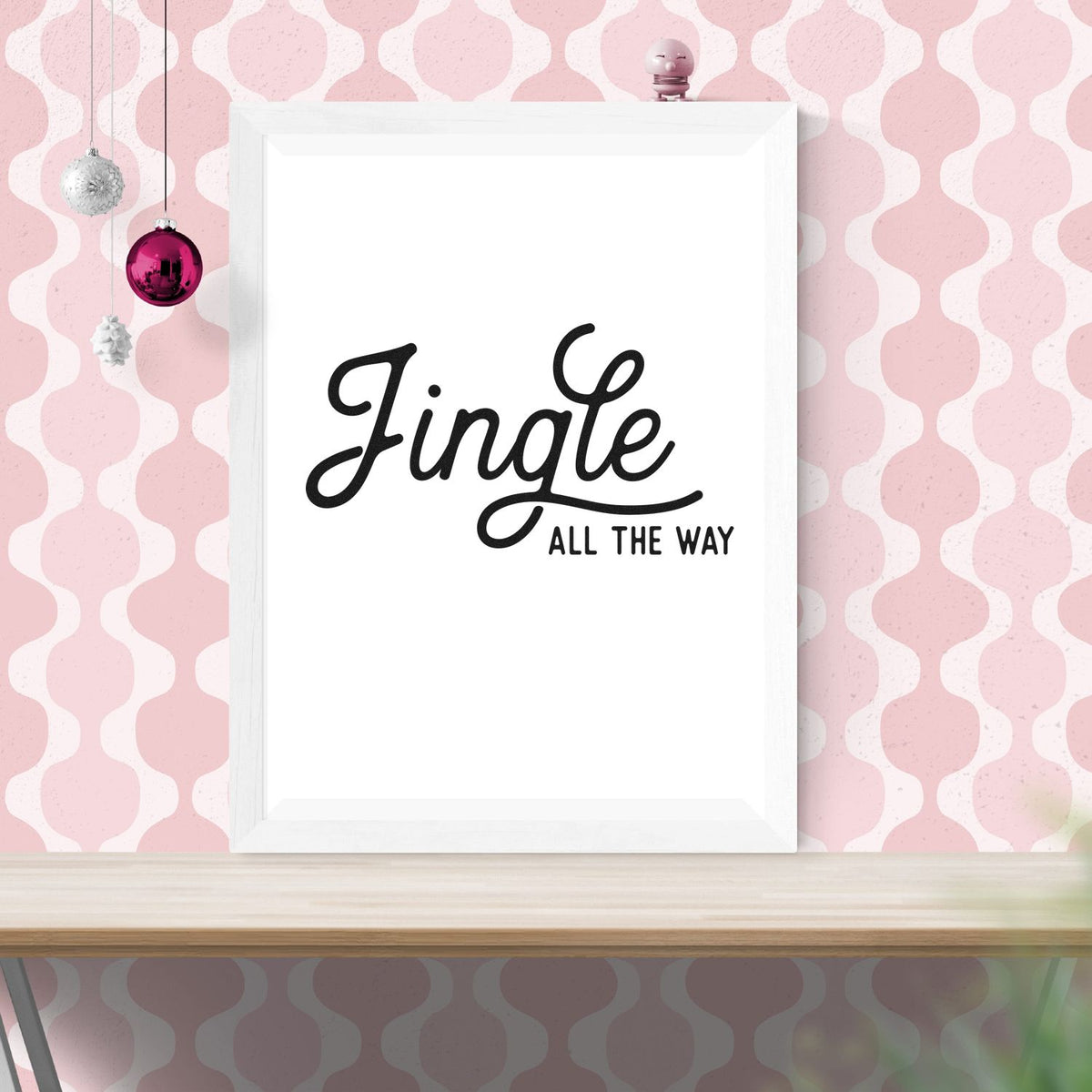 White framed holiday stamp and seal design with black Jingle all the way script on pink patterned background and ornaments.