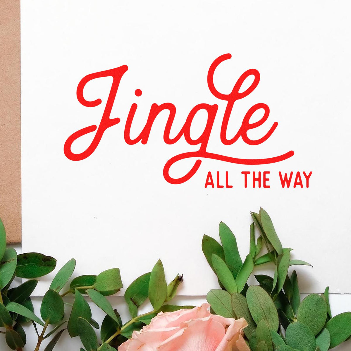 Red Jingle All the Way stamp and seal on white card, framed by green leaves and a pink rose.