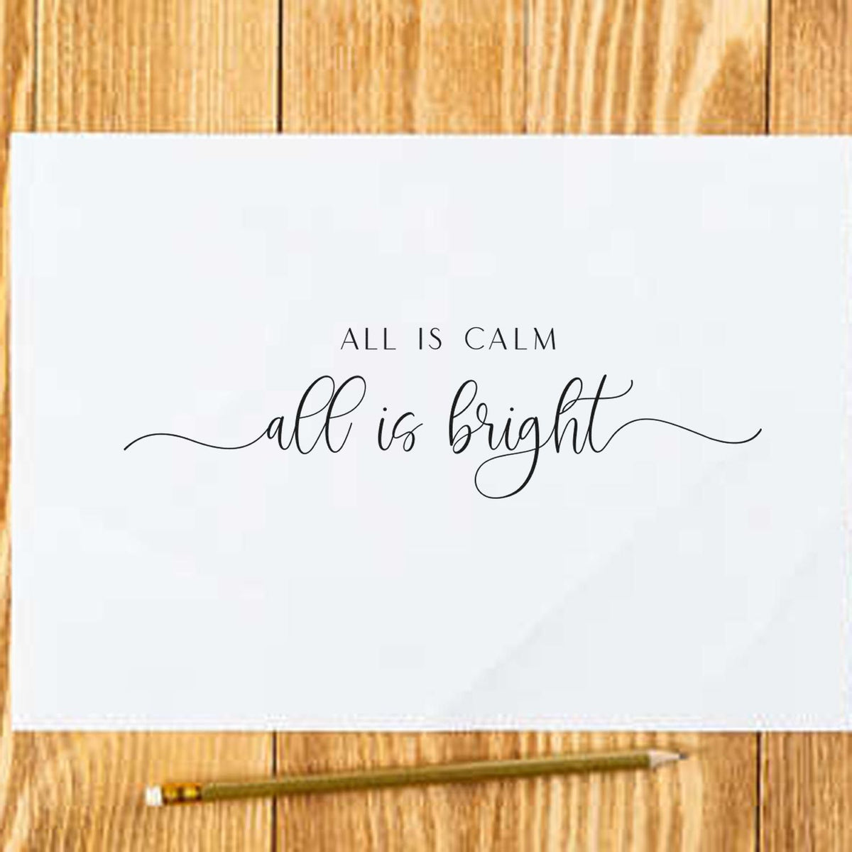 Custom stamp and seal with black All is calm, all is bright script on white paper, on a light wood surface.