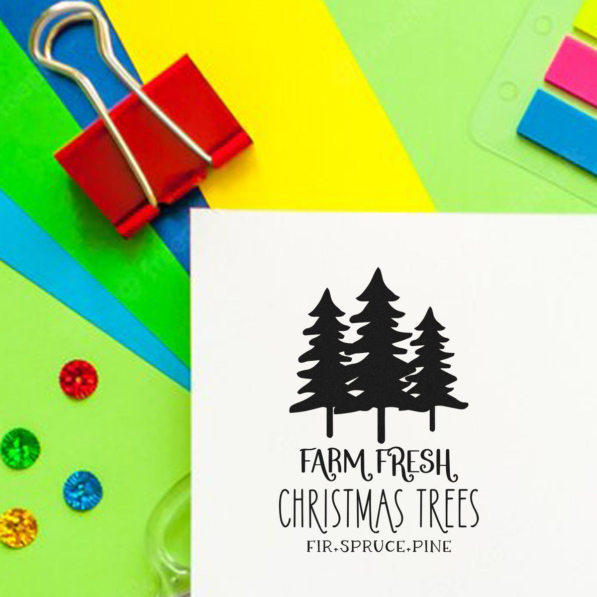Black Christmas tree stamp and seal reading Farm Fresh Christmas Trees on white card, with colorful stationery and red binder clip.