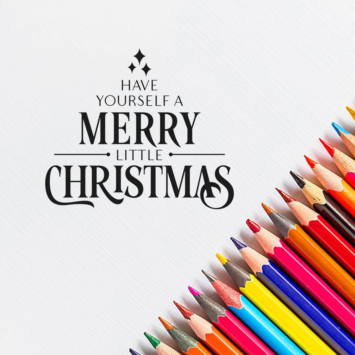 Christmas stamp design with Have yourself a merry little Christmas in black, beside a rainbow of sharpened colored pencils.