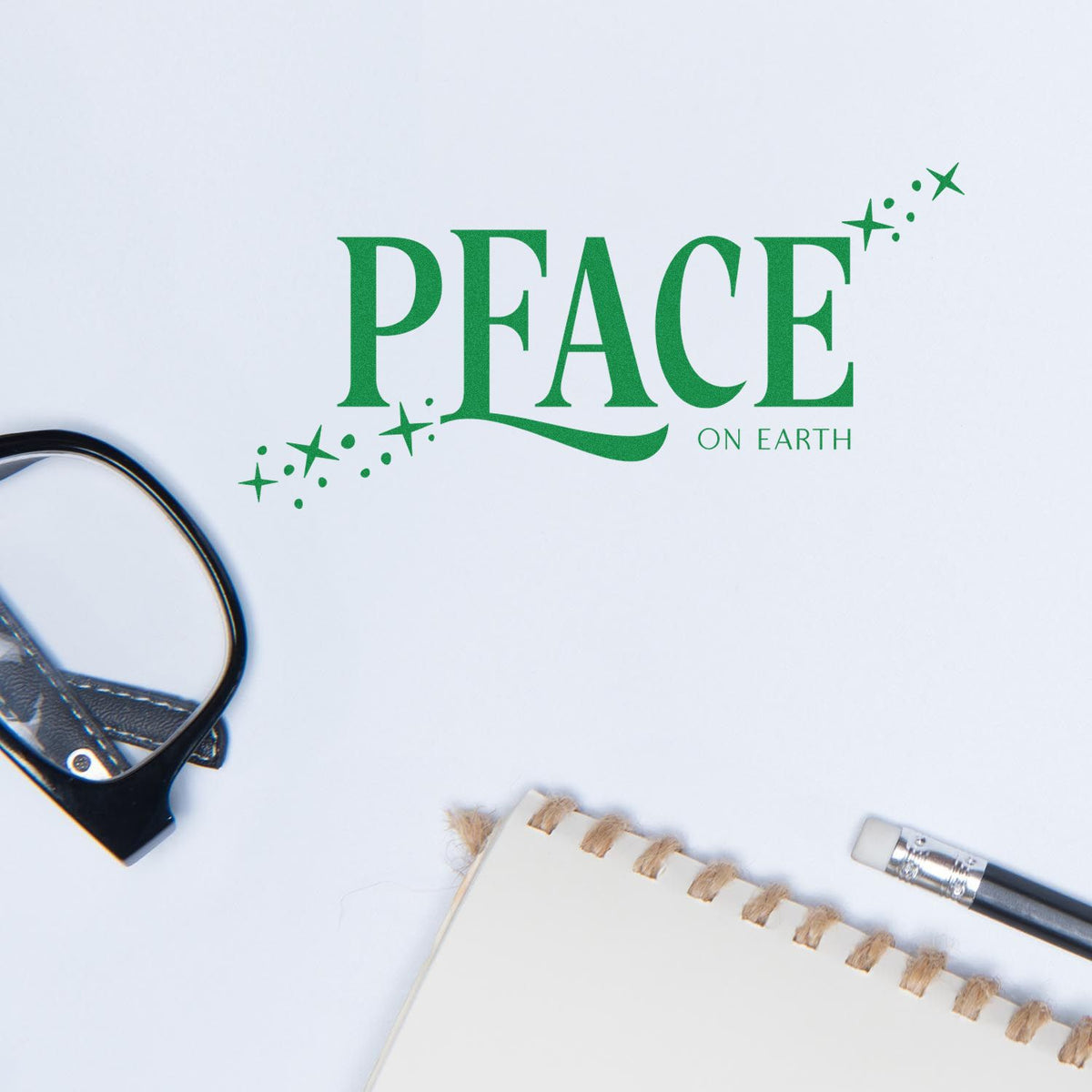 Green Peace on Earth stamp design on white paper, with sparkles and seal stamp tools on a clean desk.