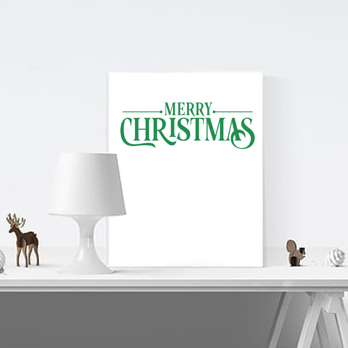 Green Merry Christmas stamp and seal on a white wall display, with a white lamp and small reindeer holiday decor.