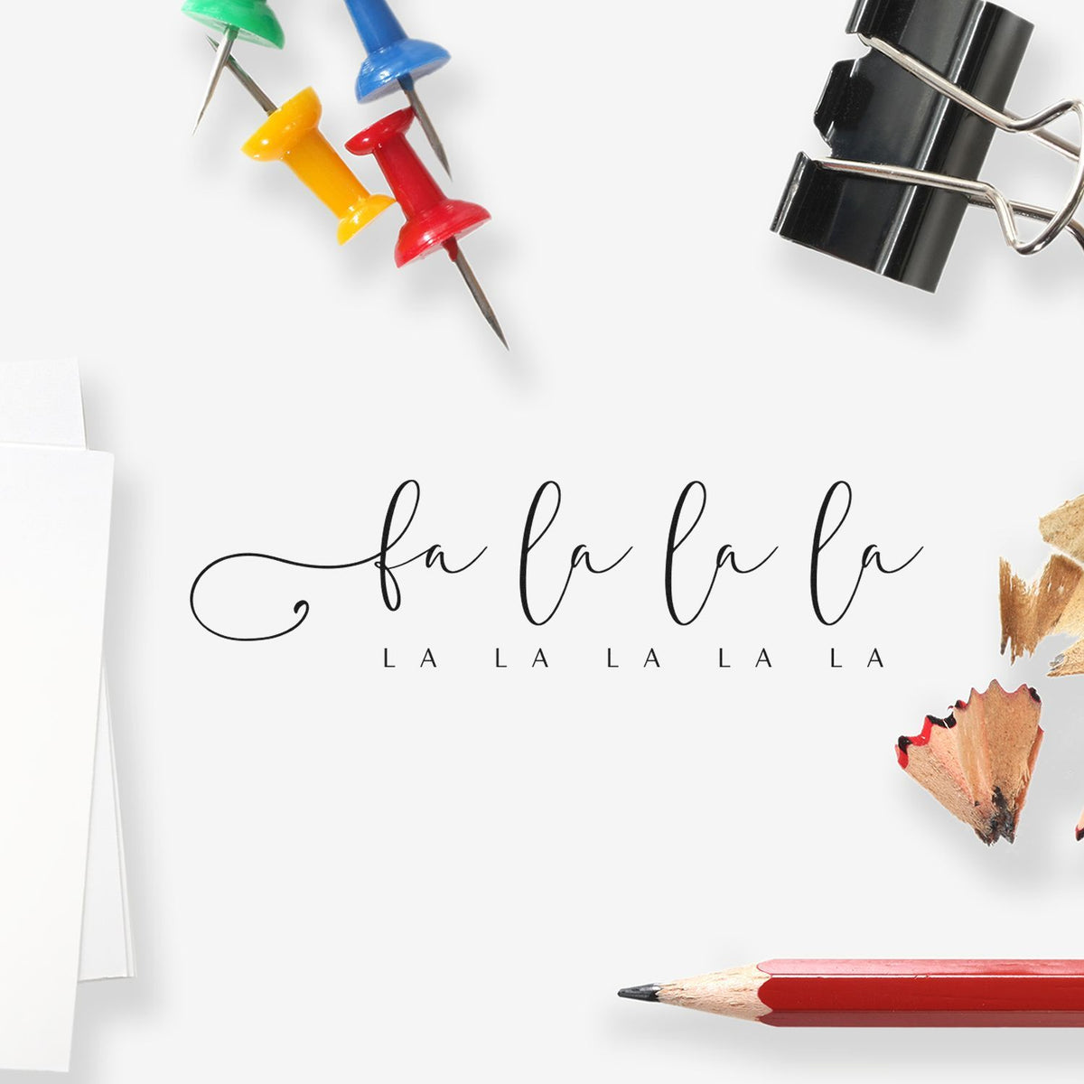 Custom stamp and seal product design with black fa la la script, colorful push pins, red pencil, and black binder clip on white.