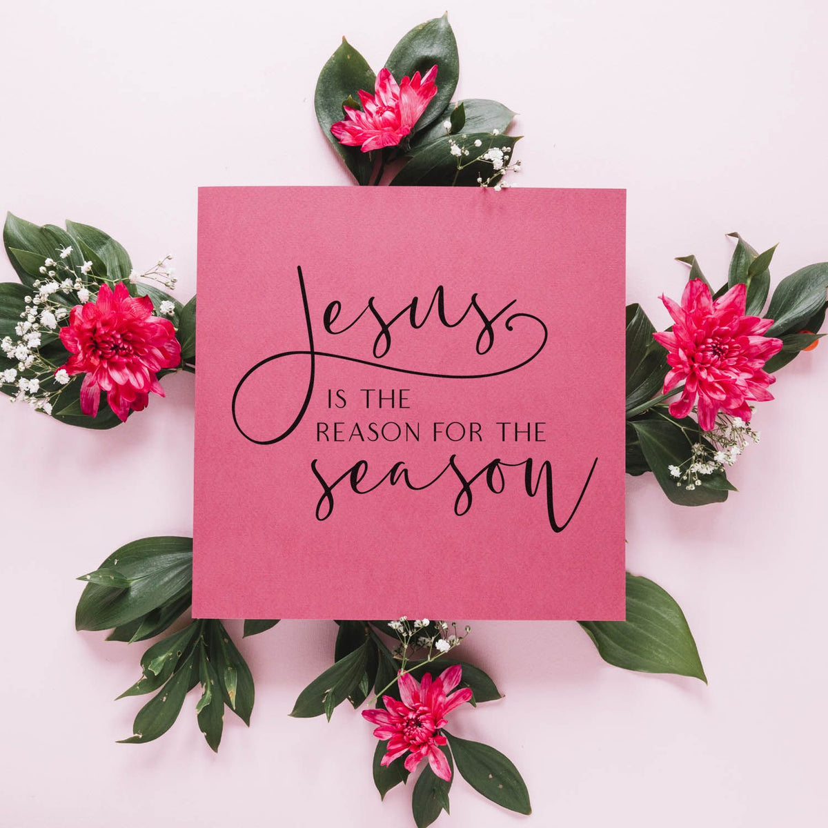 Pink Christian stamp and seal card with Jesus is the reason for the season, framed by hot pink flowers and green leaves.
