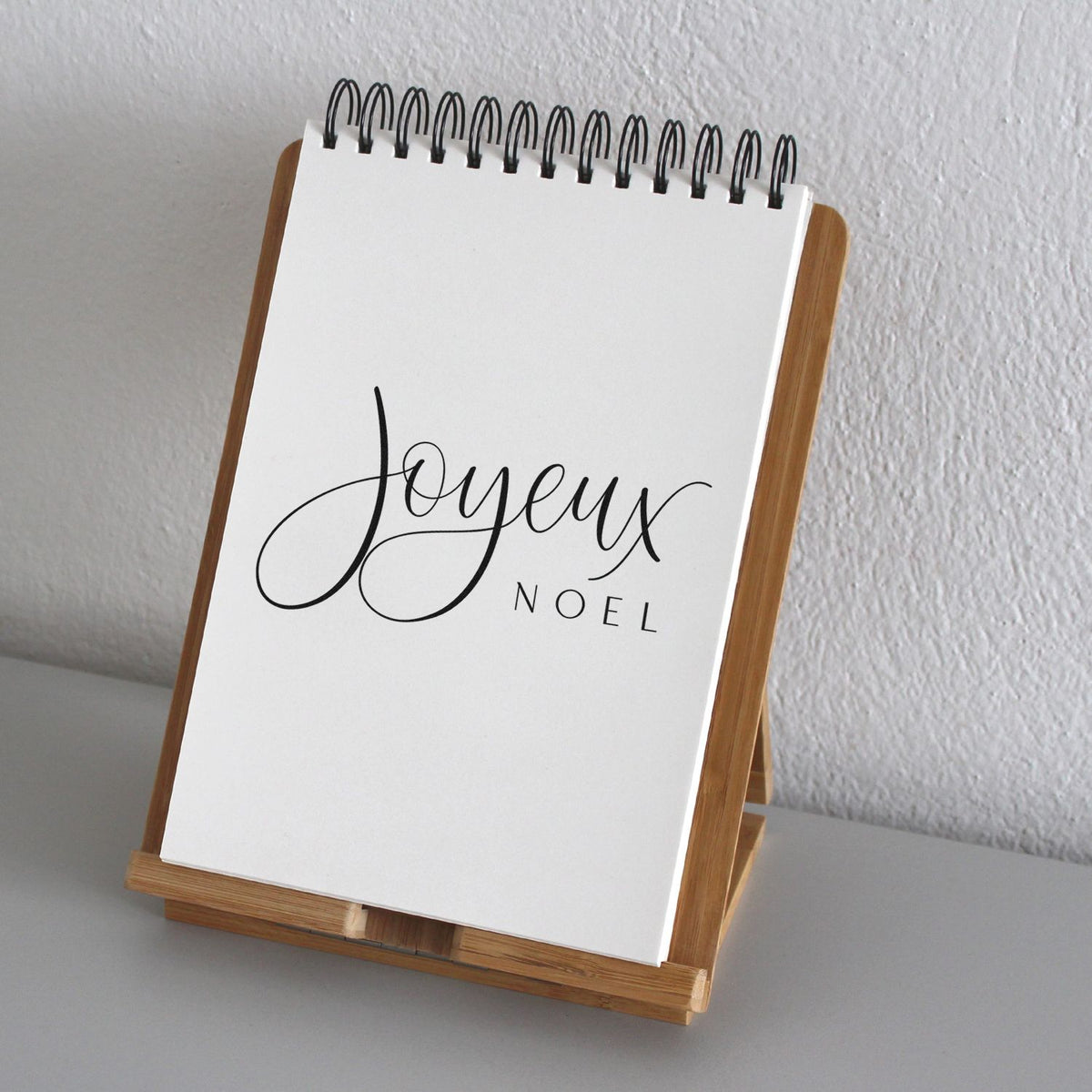 Joyeux Noel Fine Script Premium Wood-Mounted Stamp - Vintage Pro imprint stamped in brown ink. The greeting "Joyeux Noel" combines a large cursive word with small widely spaced capitals.