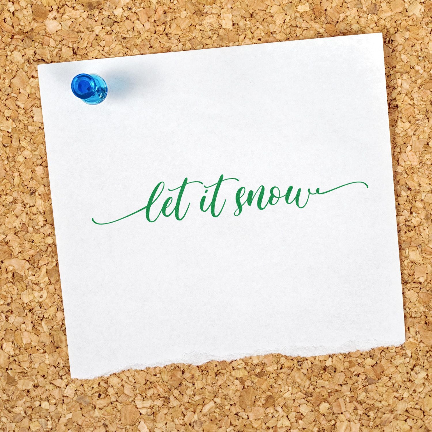 Green let it snow stamp/seal on white paper, pinned with a blue pushpin on a corkboard.