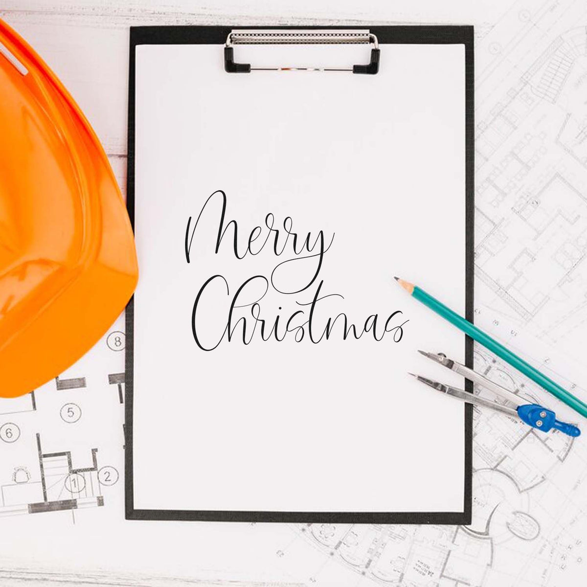 Custom stamp and seal mockup with black Merry Christmas script, orange hard hat, pencils and drafting tools on blueprints.