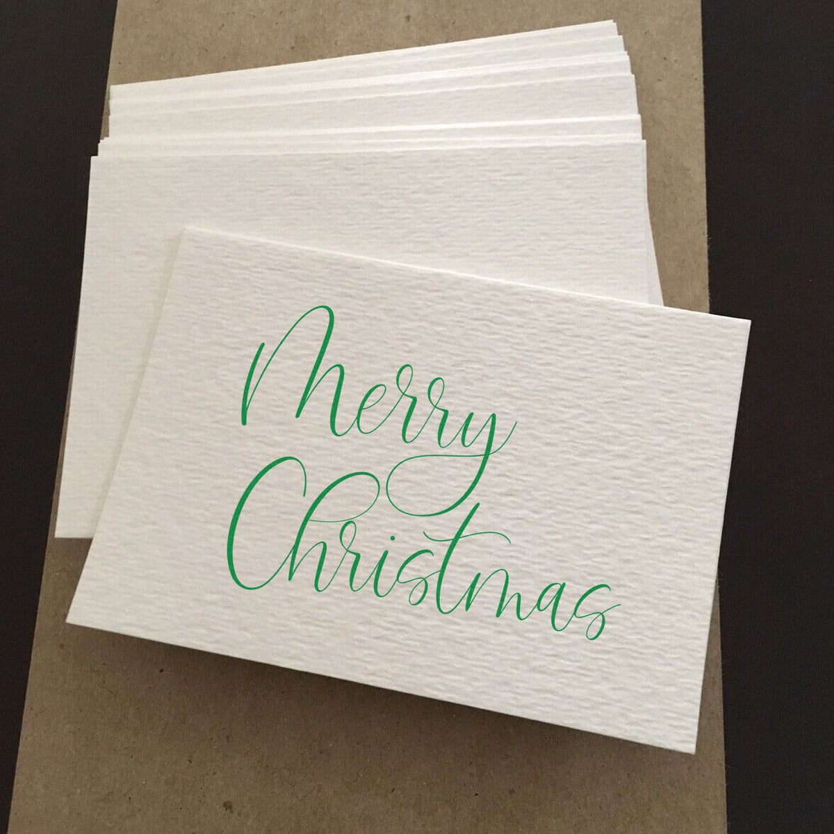 White textured stamp cards with green Merry Christmas calligraphy for holiday seals.