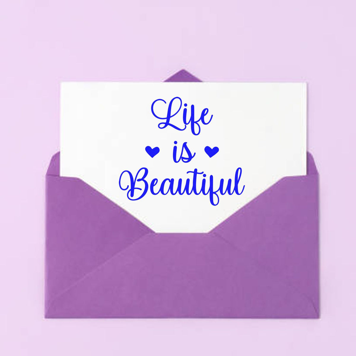 Purple envelope seal stamp with white card reading Life is Beautiful in blue script and hearts on a pink background.