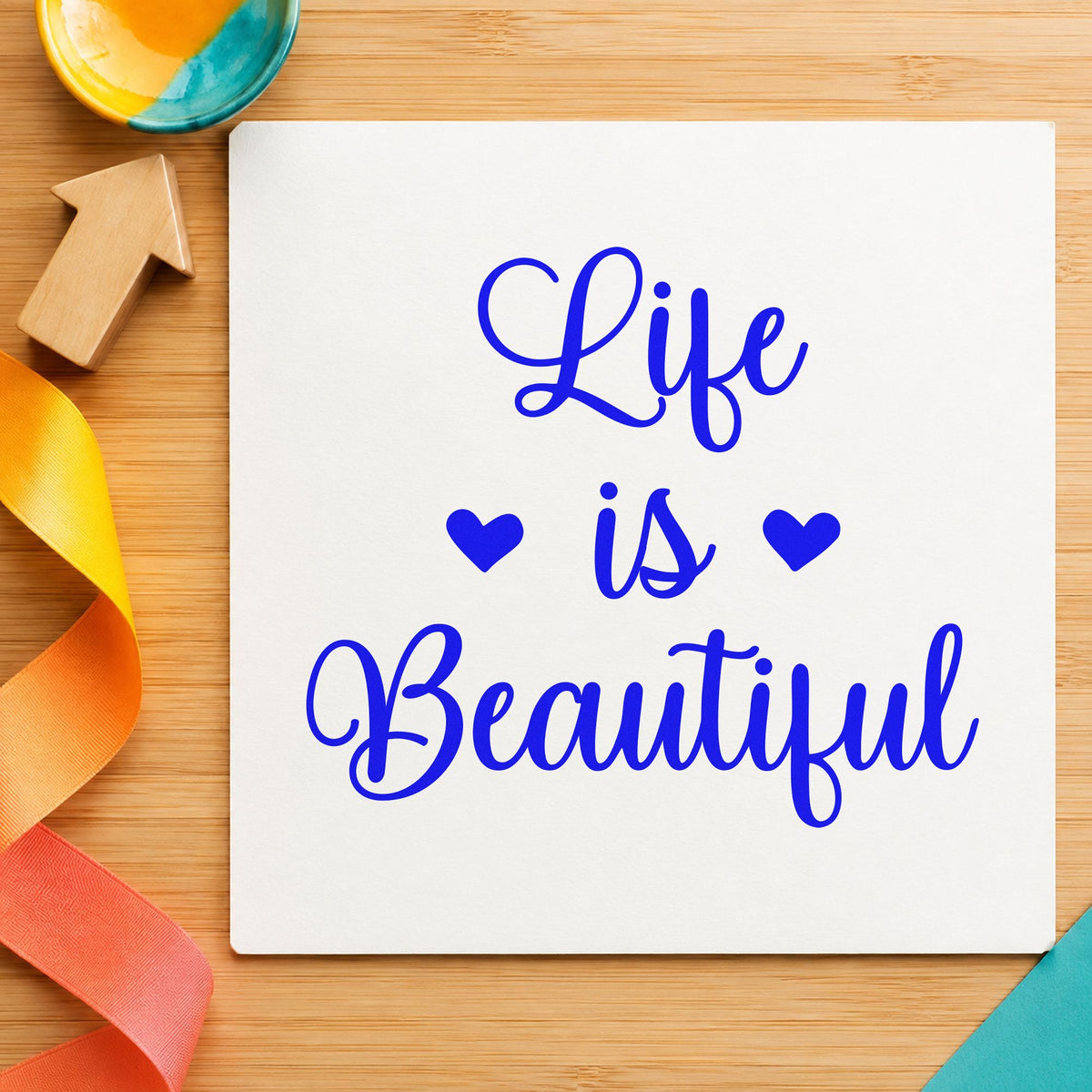 Life Is Beautiful Hearts craft stamp in blue ink on cardstock, an easy option for camera strap printing.