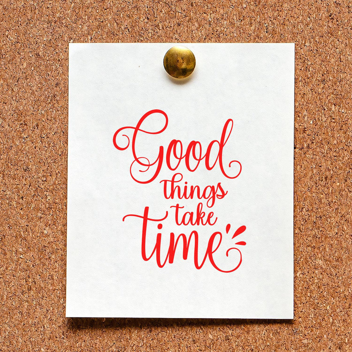 Red rubber stamp seal reading Good things take time on white card pinned to a corkboard with brass tack.