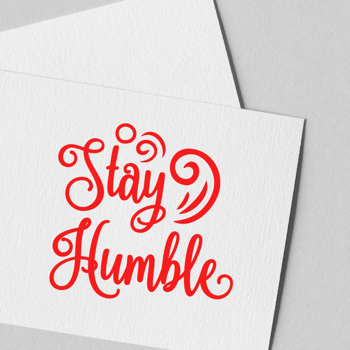 Red Stay Humble stamp design in decorative script on white textured paper, for stamp and seal products.