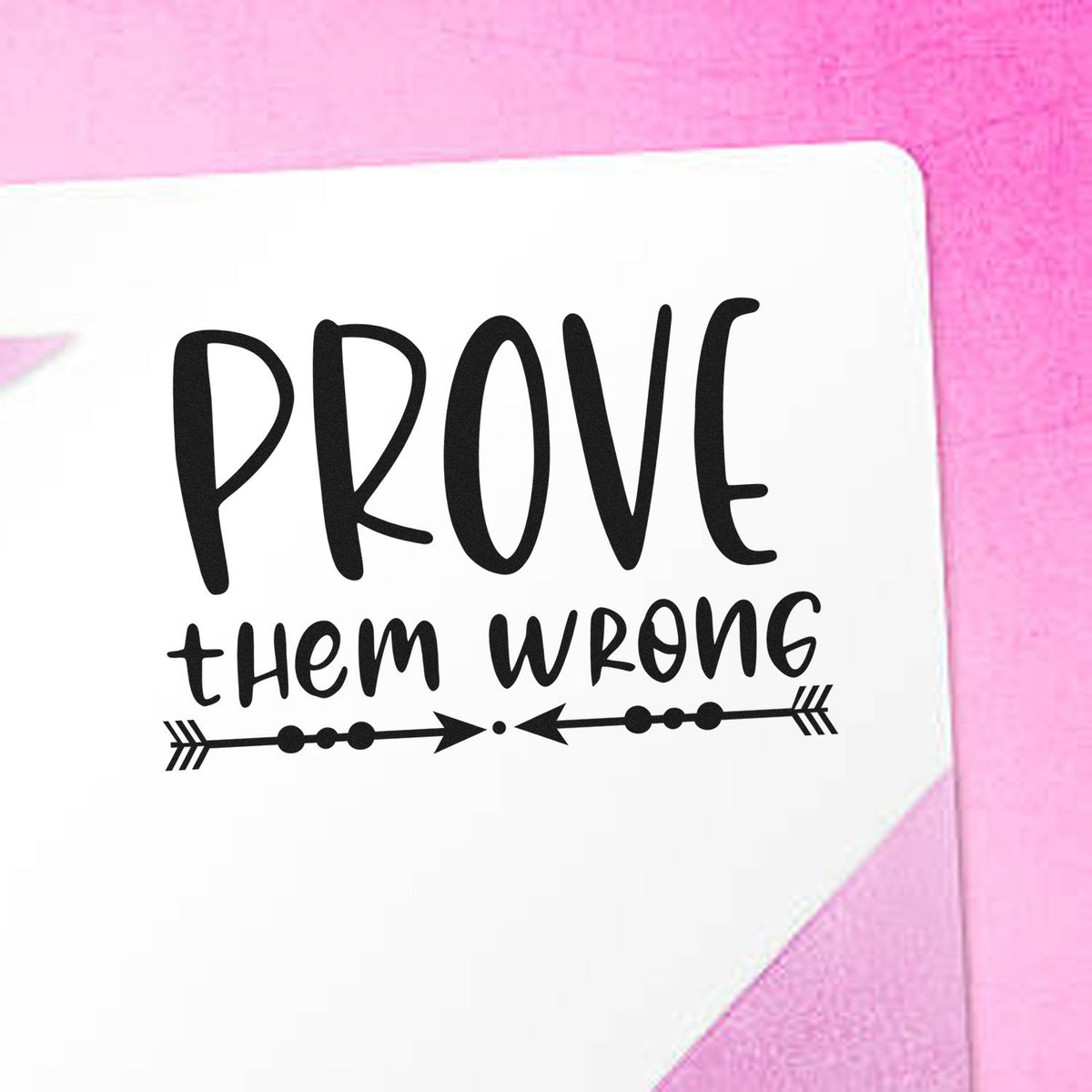 Black custom stamp/seal reading PROVE them wrong with arrow accents on a white card against a pink background.