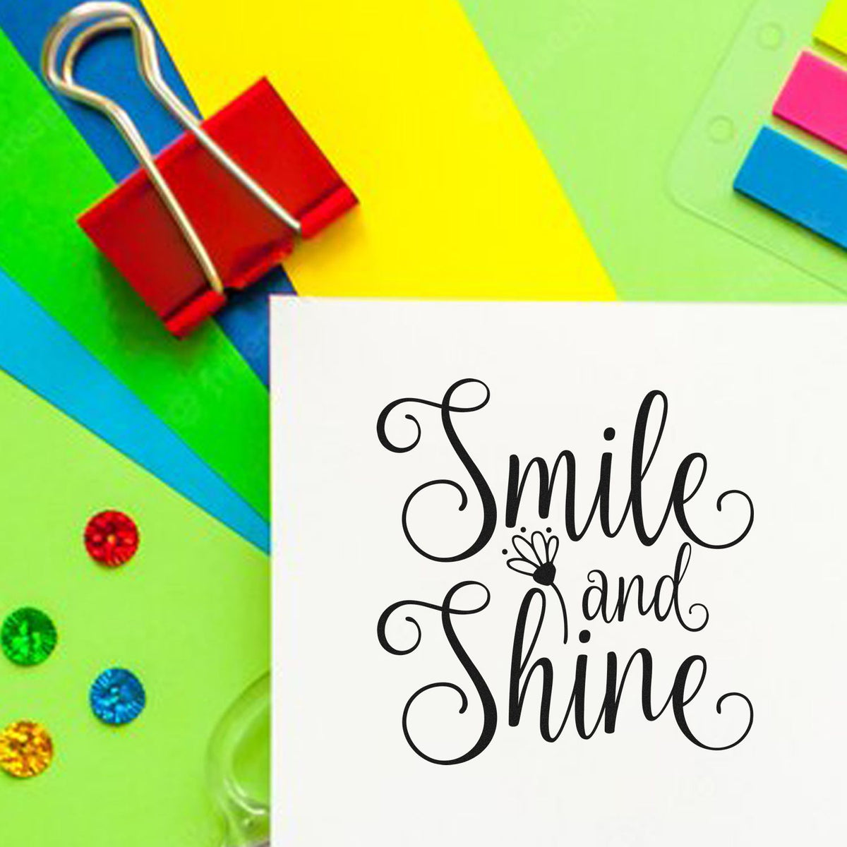 White card with black Smile and Shine stamp, colorful paper swatches, and red binder clip on bright paper.