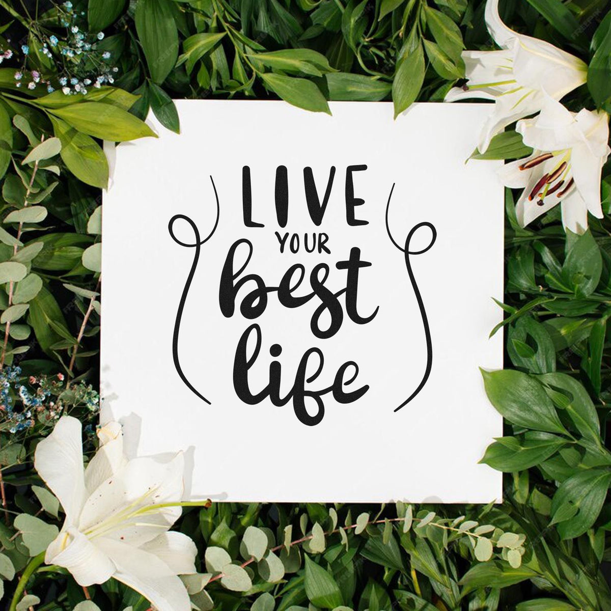 Black Live your best life stamp and seal design on white card, framed by green leaves and white lilies.