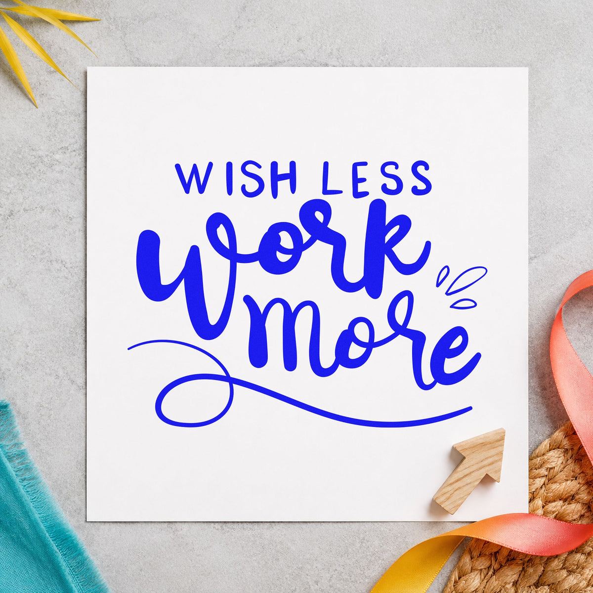 Wish Less Work More craft stamp imprinted in blue ink on paper, a design suited to framed bench wall.