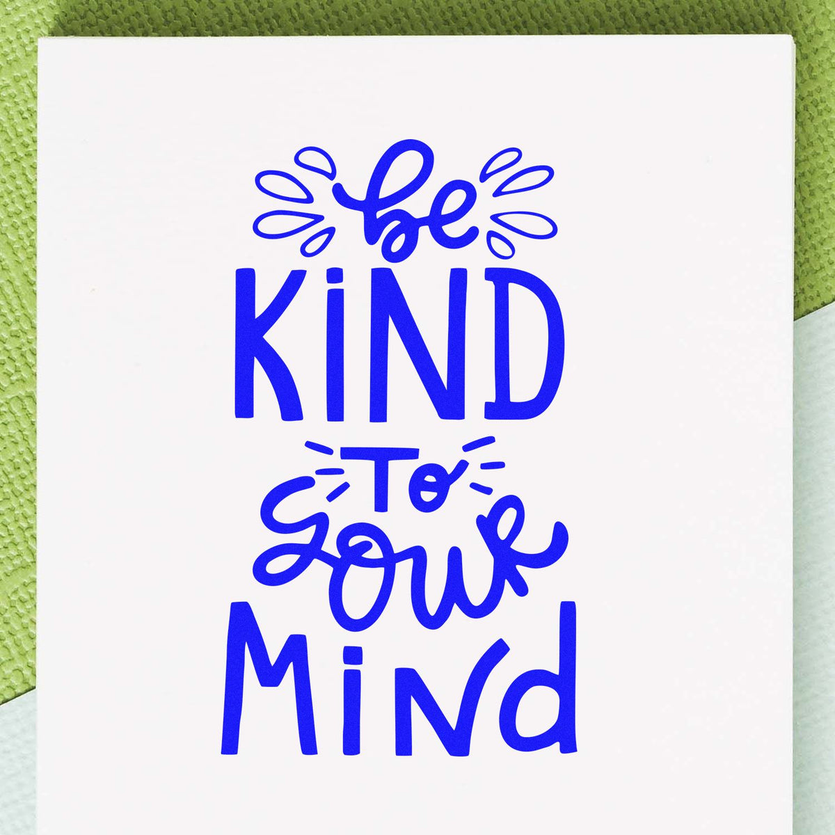 Blue Be Kind to Your Mind stamp and seal design on white paper with playful lettering and decorative accents.
