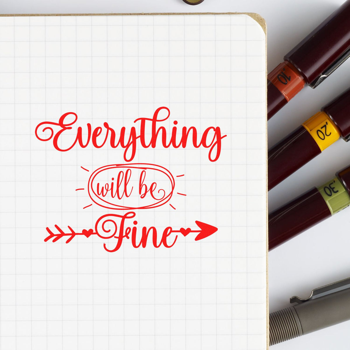 Red Everything will be fine calligraphy stamp on grid paper beside maroon stamp and seal markers in orange, yellow, and green.