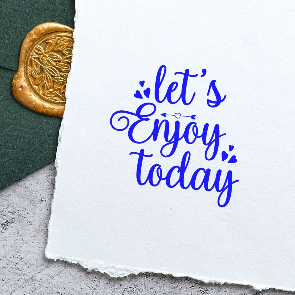 Blue lets Enjoy today calligraphy stamp on white textured paper, with a partial gold wax seal and dark green background.
