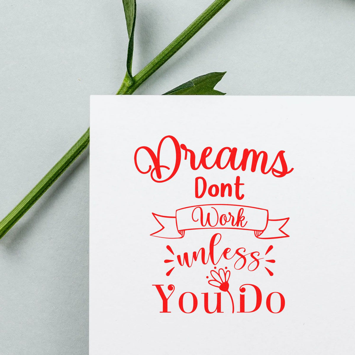 Red custom stamp/seal reading Dreams Dont Work Unless You Do on white card with green stem accents.
