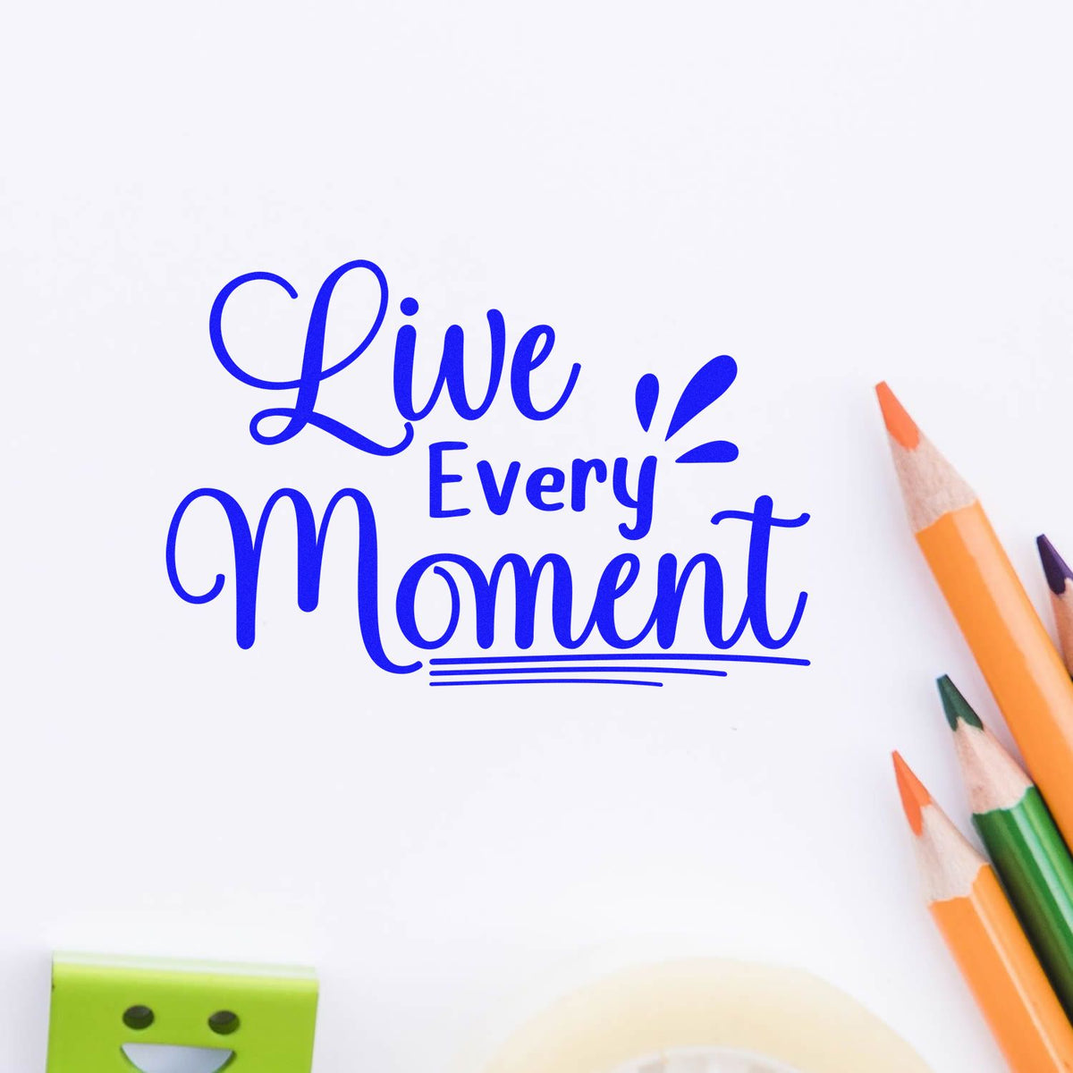 Blue Live Every Moment stamp and seal design with decorative lettering, white background, and colored pencils.