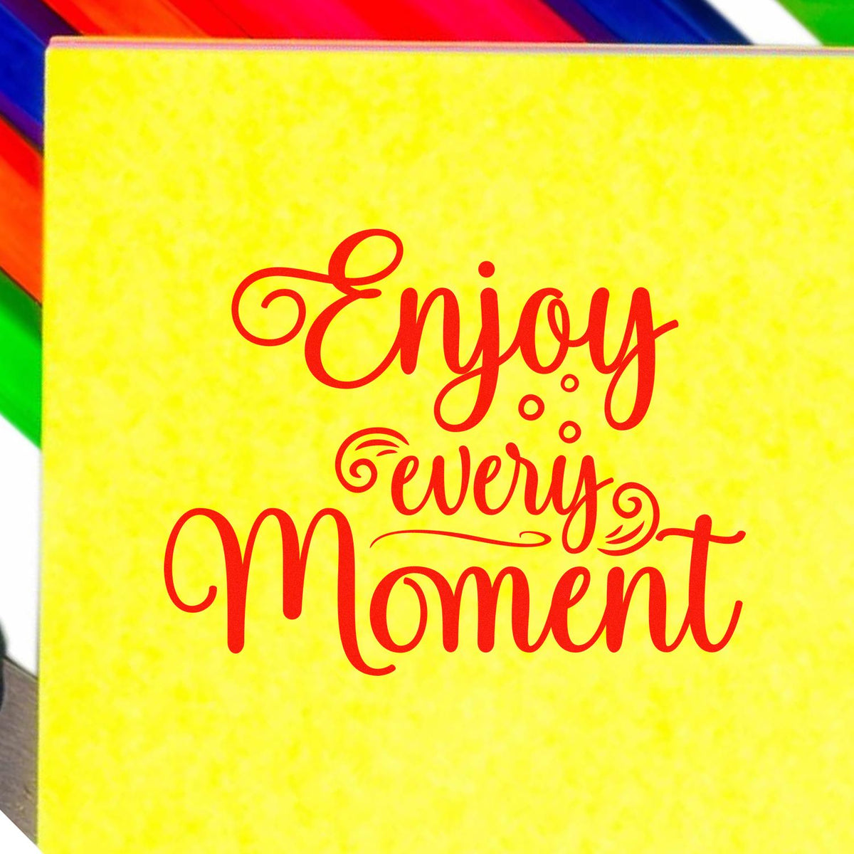 Yellow stamp seal product with red Enjoy every Moment lettering and rainbow border accents.