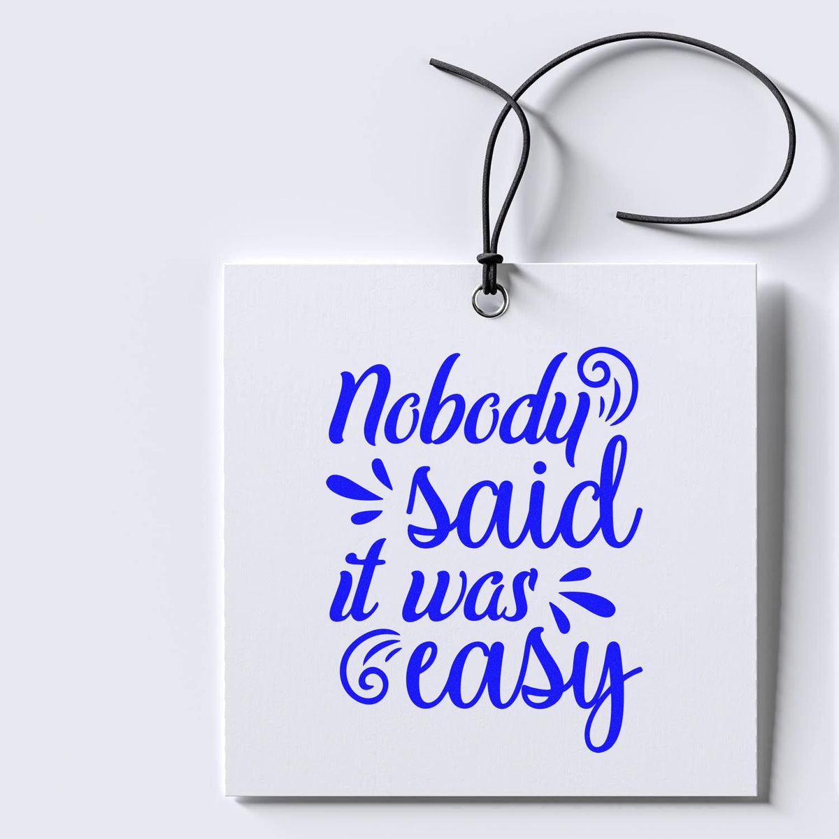 Blue custom stamp seal tag with black cord, reading Nobody said it was easy on a white background.