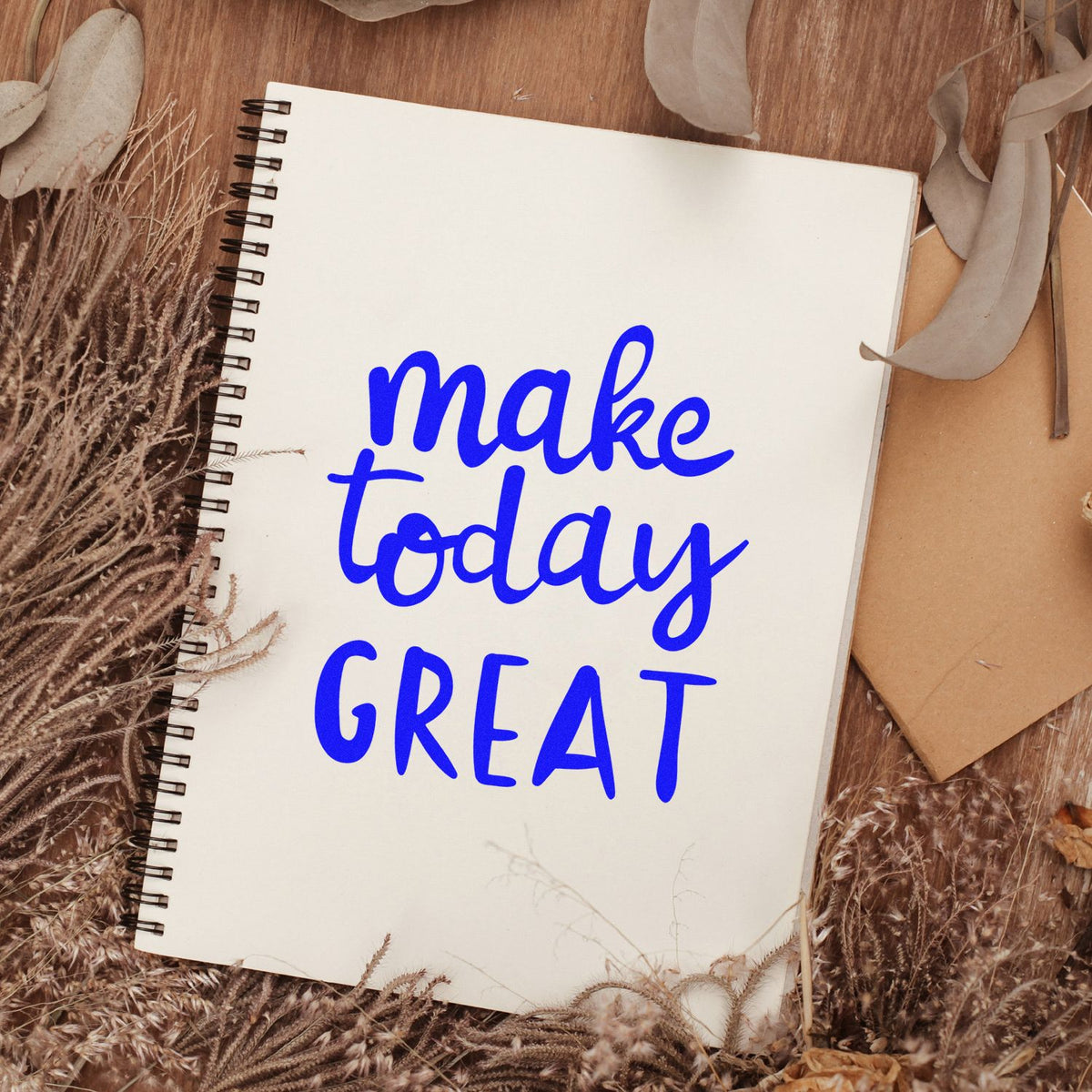 Blue make today GREAT stamp on a white spiral notebook, with dried beige foliage and kraft paper accents.