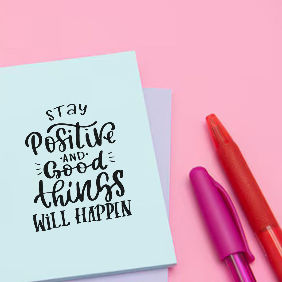 Pastel blue stamp-and-seal card with stay positive text on pink, beside red and magenta tools.