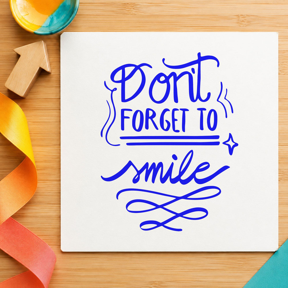 Don't Forget To Smile craft stamp in blue ink on cardstock, an easy option for staff tunic printing.